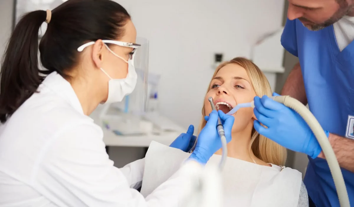 jeune femme se fait faire un détartrage chez le dentiste et son assistant