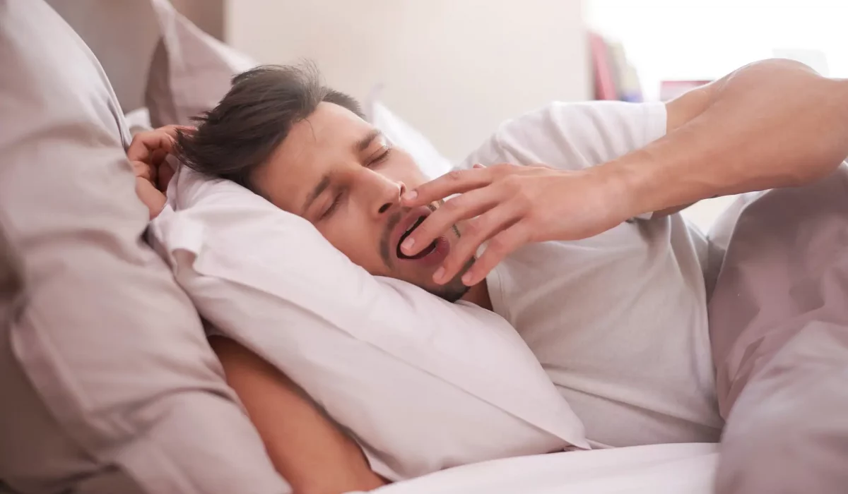 homme dans son lit qui baille